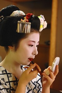 MAQUILLAGE TRADITIONNEL (DORAN) D’UNE MAIKO (APPRENTIE GEISHA), APPLICATION DU ROUGE A LEVRES (KUSHIBENI) AU PINCEAU, UNE PETITE BOUCHE (OCHOBO KUSHI) ETANT UN CRITERE DE BEAUTE, LA COIFFURE DE LA MAIKO EST UN CHIGNON EN FORME DE PECHE FENDUE (WARESHINOBU) ORNE DE RUBANS EN SOIE (KANOKO), QUARTIER DE GION, KYOTO, JAPON, ASIE 