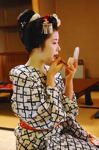 MAQUILLAGE TRADITIONNEL (DORAN) D’UNE MAIKO (APPRENTIE GEISHA), APPLICATION DU ROUGE A LEVRES (KUSHIBENI) AU PINCEAU, UNE PETITE BOUCHE (OCHOBO KUSHI) ETANT UN CRITERE DE BEAUTE, LA COIFFURE DE LA MAIKO EST UN CHIGNON EN FORME DE PECHE FENDUE (WARESHINOBU) ORNE DE RUBANS EN SOIE (KANOKO), QUARTIER DE GION, KYOTO, JAPON, ASIE 