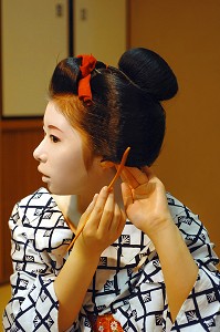 COIFFURE TRADITIONNELLE D’UNE MAIKO (APPRENTIE GEISHA), MAIKO ARRANGEANT SON CHIGNON EN FORME DE PECHE FENDUE (WARESHINOBU) ORNE DE RUBANS EN SOIE (KANOKO) AVEC UN PEIGNE (KUSHI) EN BUIS, QUARTIER DE GION, KYOTO, JAPON, ASIE 