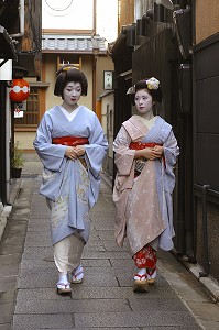 GEIKO (GEISHA), A GAUCHE, ET MAIKO (APPRENTIE) PORTANT UN KIMONO (OBEBE) FERME PAR UNE CEINTURE LARGE (OBI) ET CHAUSSEES DE SANDALES EN BOIS (OKOBO) SE PROMENANT DANS UNE RUE, QUARTIER DE GION, KYOTO, JAPON, ASIE 