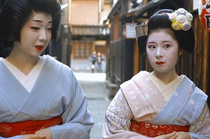 GEIKO (GEISHA), A GAUCHE, ET MAIKO (APPRENTIE) PORTANT UN KIMONO (OBEBE) FERME PAR UNE CEINTURE LARGE (OBI) ET CHAUSSEES DE SANDALES EN BOIS (OKOBO) SE PROMENANT DANS UNE RUE, QUARTIER DE GION, KYOTO, JAPON, ASIE 