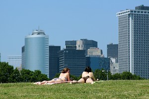 BAIN DE SOLEIL SUR UNE PELOUSE BORDANT LE FORT DE L'ILE DES GOUVERNEURS (GOVERNORS ISLAND) AVEC LES IMMEUBLES DE MANHATTAN EN FOND, NEW YORK CITY, ETAT DE NEW YORK, ETATS-UNIS 