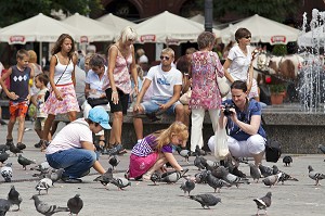 ENFANTS DONNANT A MANGER AUX PIGEONS SOUS LE REGARD DE LEUR MERE, RYNEK GLOWNY OU PLACE DU MARCHE, VIEILLE VILLE DE CRACOVIE, POLOGNE 