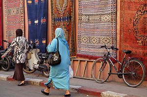 FEMMES VOILEES PASSANT DEVANT DES TAPIS BERBERES, ENTREE DU SOUK (MARCHE AUX TAPIS), AU COEUR DE LA MEDINA, MARRAKECH, MAROC 