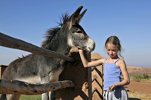 PETITE FILLE CARESSANT UN ANE, DOMAINE TOURISTIQUE DE TERRES D’AMANAR, TAHANAOUTE, AL HAOUZ, MAROC 