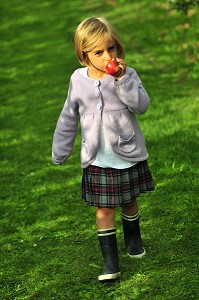 PETITE FILLE MANGEANT UNE POMME DANS SON JARDIN 