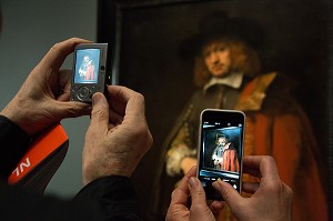 PHOTOGRAPHIE AVEC APPAREIL ET TELEPHONE PORTABLE DEVANT LA TOILE DU PORTRAIT DE JEAN SIX, VISITEUR DEVANT L'EXPOSITION DU PEINTRE REMBRANDT, MUSEE RIJKSMUSEUM, VILLE D'AMSTERDAM, PAYS-BAS 