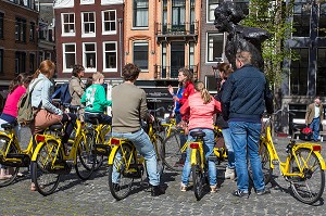GROUPE DE TOURISTES A VELO AVEC UNE GUIDE TOURISTIQUE DEVANT LA STATUE DE MULTATULI SUR LE PONT TORENSLUIS, SINGEL, VILLE D'AMSTERDAM, PAYS-BAS 