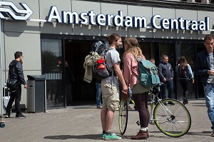 COUPLE D'AMOUREUX EN VELO DEVANT LA GARE DE CENTRAL STATION (AMSTERDAM CENTRAAL), VILLE D'AMSTERDAM, PAYS-BAS 