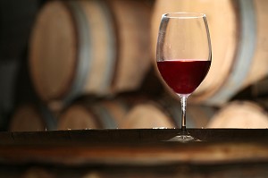 VERRE DE VIN ROUGE DANS UN ENVIRONEMENT DE CAVE ET BARRIQUES 