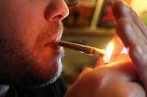 CONSOMMATEUR DE CANNABIS EN TRAIN DE S'ALLUMER UN JOINT OU PETARD 