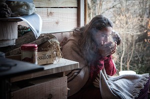 LORELEI BOIT SON BOL DE THE AU PETIT MATIN A L'ENTREE DE SA CABANE, ELLE A TOUT QUITTE POUR CONSTRUIRE ET HABITER SA CABANE EN BOIS AU MILIEU DE LA CREUSE, FRANCE 