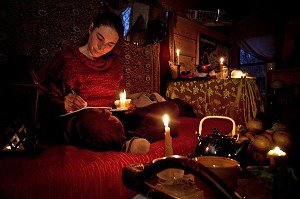 LORELEI ECRIT SON JOURNAL A LA LUMIERE DE LA BOUGIE, ELLE A TOUT QUITTE POUR CONSTRUIRE ET HABITER SA CABANE EN BOIS AU MILIEU DE LA CREUSE, FRANCE 