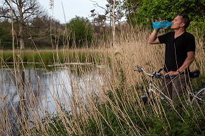 CYCLISTE EN TRAIN DE BOIRE SUR LES BORDS D'UN ETANG, DOMAINE DE CHAMBORD, ITINERAIRE DE LA LOIRE A VELO, LOIR-ET-CHER (41), FRANCE 