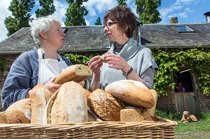 BLANDINE ZOUTARD FAISANT GOUTER SON PAIN BIO A NATHALIE DE WEVER, COMMERCANTE ET ADHERENTE DU MOUVEMENT LOCAVORE, DEVANT SA BOULANGERIE, FERME DE SAINT-MAMERT, BUIS-SOUS-DANVILLE, EURE (27), FRANCE 