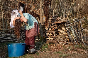 LORELEI SE LAVE LES CHEVEUX APRES AVOIR FAIT CHAUFFER L'EAU DANS LA BOUILLOIRE, ELLE A TOUT QUITTE POUR CONSTRUIRE ET HABITER SA CABANE EN BOIS AU MILIEU DE LA CREUSE, FRANCE 