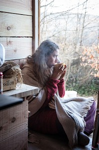 LORELEI BOIT SON BOL DE THE AU PETIT MATIN A L'ENTREE DE SA CABANE, ELLE A TOUT QUITTE POUR CONSTRUIRE ET HABITER SA CABANE EN BOIS AU MILIEU DE LA CREUSE, FRANCE 