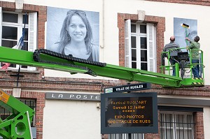 COLLAGE AVEC UNE NACELLE DES PHOTOS GEANTES SUR LES MURS (LA POSTE) DE LA VILLE POUR LE FESTIVAL CULTUREL RUGL'ART, RUGLES, (27) EURE, FRANCE 