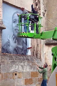 COLLAGE AVEC UNE NACELLE DES PHOTOS GEANTES SUR LES MURS DE LA VILLE POUR LE FESTIVAL CULTUREL RUGL'ART, RUGLES, (27) EURE, FRANCE 