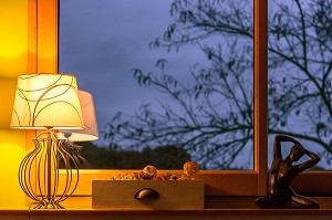 ECLAIRAGE INTERIEUR D'UNE MAISON A LA TOMBEE DE LA NUIT AVEC VUE SUR LE JARDIN 