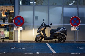 SCOOTER DEVANT DES PLACES HANDICAPEES DANS LES PHARE D'UNE VOITURE, BOURGES, (18) CENTRE, VAL DE LOIRE, FRANCE 