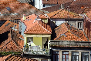 FEMME EN TRAIN D'ETENDRE SON LINGE SUR SON BALCON AU MILIEU DES TOITS DE TUILES ROUGES, VILA NOVA DE GAIA, PORTO, PORTUGAL 