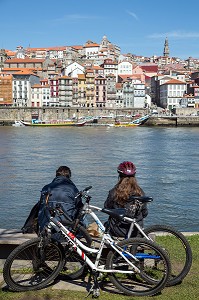 COUPLE DE CYCLISTES SUR LES BERGES DU DOURO FACE A LA VILLE DE PORTO, VILA NOVA DE GAIA, PORTUGAL 