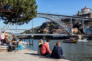 TOURISTES SUR LES BORDS DU  DOURO DEVANT LE PONT LUIS 1ER AVEC LE DOME DU MONASTERE DE SERRA DO PILAR, CAIS DA REBEIRA, PORTO, PORTUGAL 