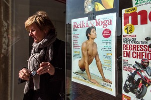 FEMME SORTANT D'UNE LIBRAIRIE AVEC LA COUVERTURE D'UN MAGAZINE (HOMME EN SEANCE DE YOGA), VILLE BALNEAIRE D'ESPINHO, PORTUGAL 