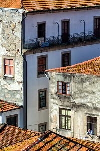 HABITANT EN TRAIN D'ETENDRE SON LINGE A SA FENETRE DANS UNE RUELLE AUX TOITS DE TUILES ROUGES, VILA NOVA DE GAIA, PORTO, PORTUGAL 