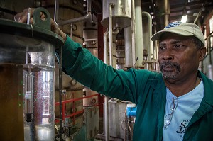 OUVRIER A LA PRODUCTION POUR MESURER LE TAUX D'ALCOOL EN SORTIE D'ALAMBIC, DISTILLERIE MARTINIQUAISE DE RHUM DES PLANTATIONS SAINT-JAMES, SAINTE-MARIE, MARTINIQUE, ANTILLES FRANCAISES, FRANCE 