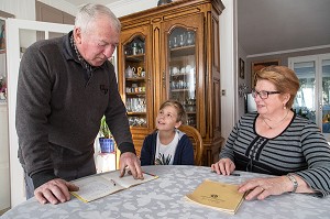 COUPLE DE PERSONNES AGEES AVEC LEUR PETIT-FILS EN TRAIN DE FAIRE LES DEVOIRS D'ECOLE LA MAISON, VILLE DE VERNEUIL-SUR-AVRE (27), FRANCE 