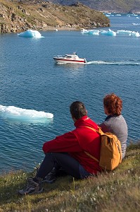 COUPLE ASSIS DEVANT LE SPECTACLE OFFERT PAR LES ICEBERGS FLOTTANT DANS LE FJORD DE LA BAIE DE NARSAQ, GROENLAND 