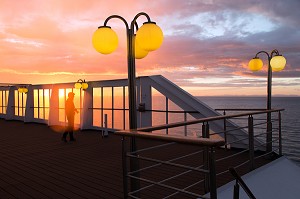 PHOTOGRAPHE DEVANT UN COUCHER DE SOLEIL SUR LE PONT SUPERIEUR DU PAQUEBOT, BATEAU DE CROISIERE ASTORIA DEVANT LES COTES ISLANDAISES, ISLANDE 