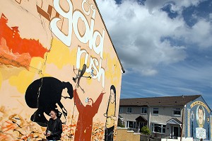 FEMME DEVANT LES FRESQUES MURALES SUR LES MURS DES MAISONS DE SHANKILL ROAD, HOPEWELL CRESCENT, QUARTIER OUEST PROTESTANT, BELFAST, ULSTER, IRLANDE DU NORD 