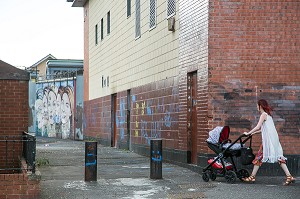 FEMME AVEC SA POUSSETTE DEVANT LES PEINTURES MURALES, QUARTIER OUEST CATHOLIQUE DE ALBERT STREET, BELFAST, ULSTER, IRLANDE DU NORD 