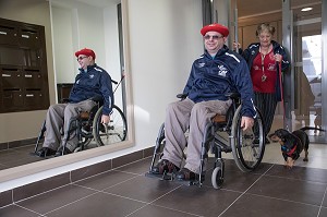 HOMME HANDICAPE PHYSIQUE DANS SON FAUTEUIL ROULANT DANS LE HALL D'IMMEUBLE, CHARTRES (28), FRANCE 