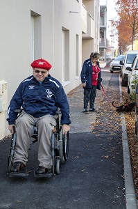 HOMME HANDICAPE PHYSIQUE DANS SON FAUTEUIL ROULANT SUR LE TROTTOIR, CHARTRES (28), FRANCE 