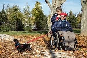 HOMME HANDICAPE PHYSIQUE DANS SON FAUTEUIL ROULANT AVEC SA FEMME ET SON CHIEN DANS LA PARC EN AUTOMNE, CHARTRES (28), FRANCE 