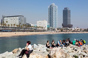 GROUPE DE JEUNES SUR LES ROCHERS AU BORD DE LA PLAGE, PASSEIG MARITIM DE LA BARCELONETA, BARCELONE, CATALOGNE, ESPAGNE 