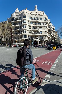 CYCLISTE DEVANT LA FACADE DE LA CASA MILA DE L'ARCHITECTE ANTONIO GAUDI, PASSEIG DE GRACIA, BARCELONE, CATALOGNE, ESPAGNE 