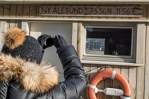 FEMME PHOTOGRAPHIANT SON ARRIVEE SUR LE PORT DU VILLAGE DE NY ALESUND, LOCALITE LA PLUS AU NORD DU MONDE (78 56N), SPITZBERG, SVALBARD, OCEAN ARCTIQUE, NORVEGE 