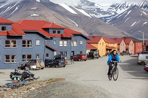 FEMME A VELO ET MAISONS COLOREES EN BOIS, VILLE DE LONGYEARBYEN, LA PLUS SEPTENTRIONALE DE LA TERRE, SPITZBERG, SVALBARD, OCEAN ARCTIQUE, NORVEGE 
