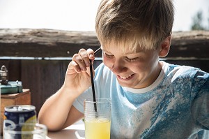 ADOLESCENT SOURIANT DEVANT SON VERRE DE SODA (BOISSON SUCREE GAZEUSE) 