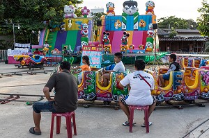 ENFANTS JOUANT DANS UN MANEGE SUR UNE PLACE, BANG SAPHAN, PROVINCE DE PRACHUAP KHIRI KHAN, THAILANDE 