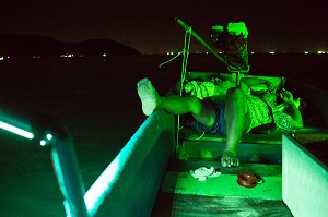 PECHE DE NUIT AUX CALAMARS, HOMME SE REPOSANT LORS D'UNE BALADE SUR L'EAU DE NUIT, GOLFE DE THAILANDE, BANG SAPHAN, PROVINCE DE PRACHUAP KHIRI KHAN, THAILANDE 