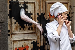 CUISINIERE DEVANT LA PORTE DE SON RESTAURANT, STREET-ART DANS LES RUE DE FUNCHAL, GRAFFITIS SUR LA FACADE DES MAISONS, FUNCHAL, ILE DE MADERE, PORTUGAL 