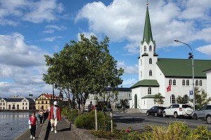 PROMENEUR AU BORD DU LAKE TJORNIN DEVANT L'EGLISE FRIKIRKJAN, REYKJAVIK, ISLANDE 