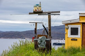 SCULPTURE DE PIERRE DEVANT FIL A LINGE, MAISON TRADITIONNELLE COLOREE JAUNE, VILLE DE QAQORTOQ, GROENLAND, DANEMARK 