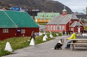 HOMME ASSIS SUR UN BANC AVEC SON CHIEN PORTANT UNE PAIRE DE LUNETTES DE SOLEIL DEVANT L'EGLISE DOWNLOAD, VILLE DE QAQORTOQ, GROENLAND, DANEMARK 